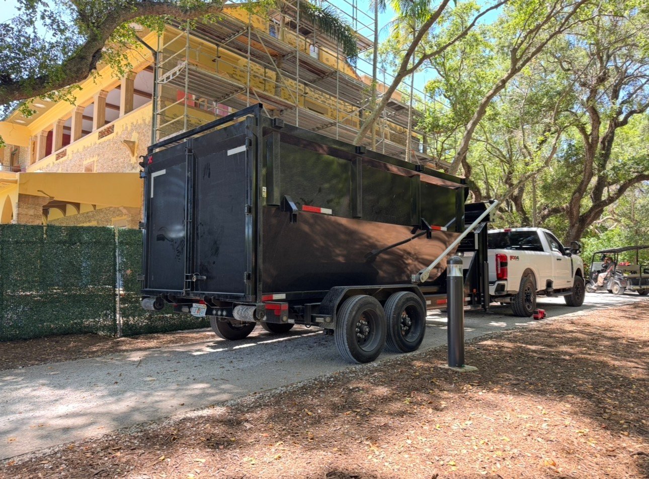 Construction dumpster rental Miami. Barraza Industries roll-off bin and Ford F-350 on luxury home construction site with scaffolding