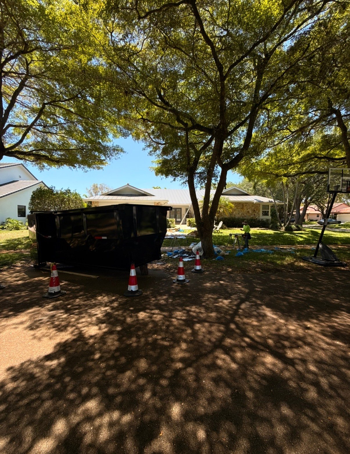 Residential dumpster rental Coral Gables Miami. Barraza Industries roll-off bin and working crew on shaded driveway